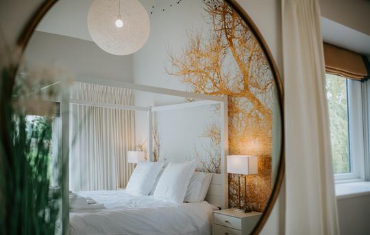 Master bedroom with four poster through mirror 