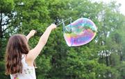 Girl playing with a colourful bubble on our meadow